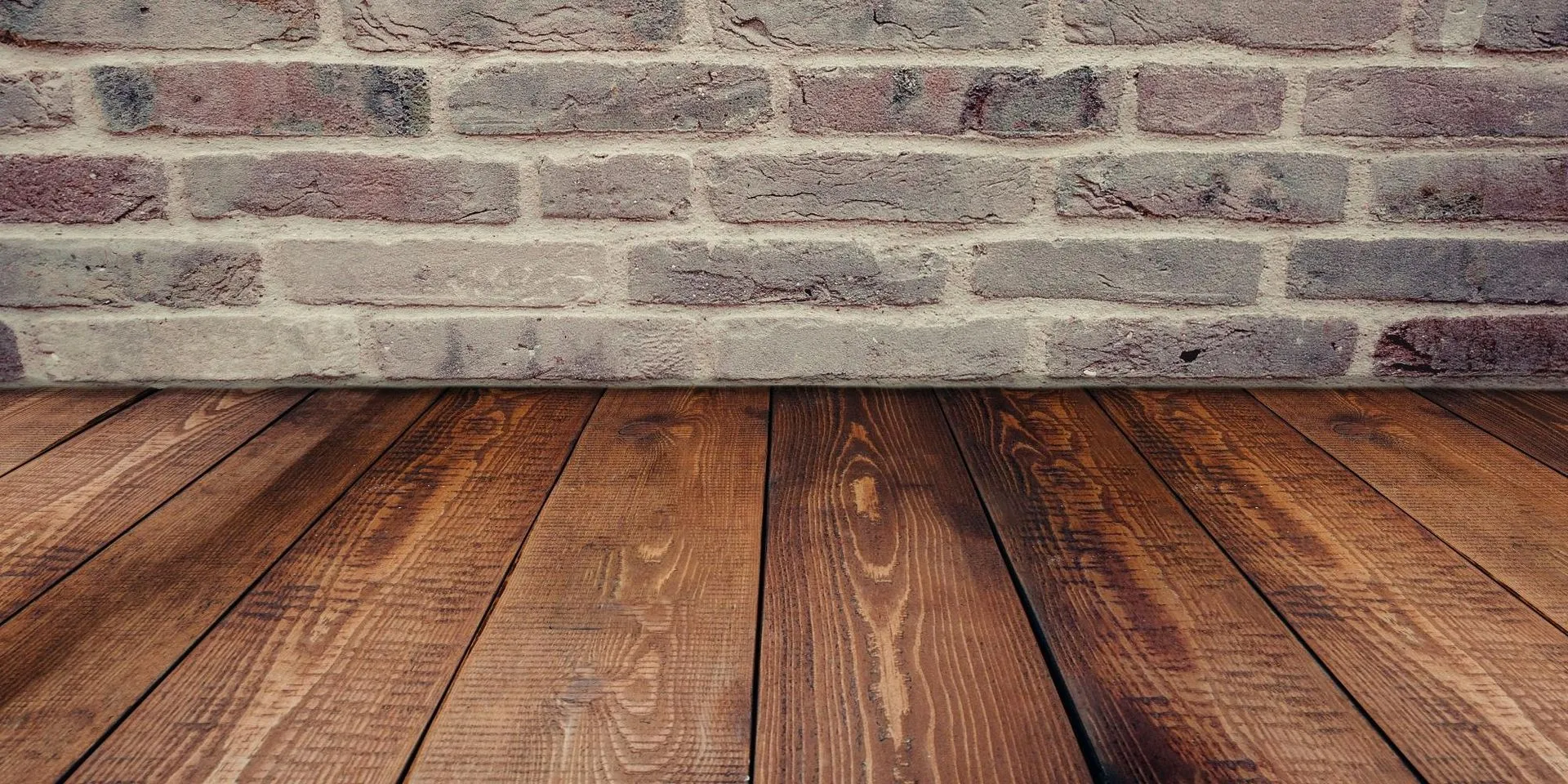 Wooden floorboards against a light gray brick wall background